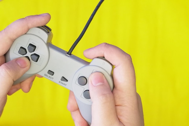 Close-up of hands holding game controller against yellow background