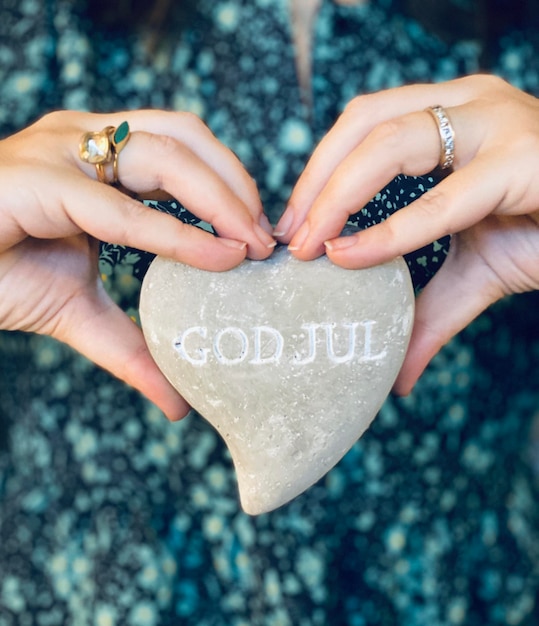 Photo close-up of hands holding heart shape stone