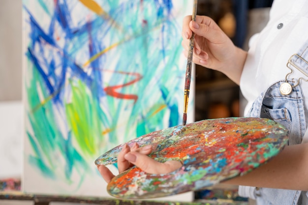 Photo close up hands holding palette and brush