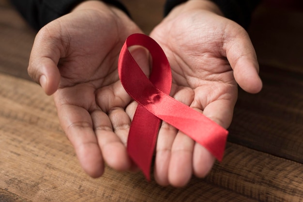 Close-up of hands holding red ribbon over wooden table