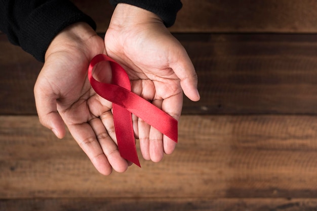Close-up of hands holding red ribbon over wooden table