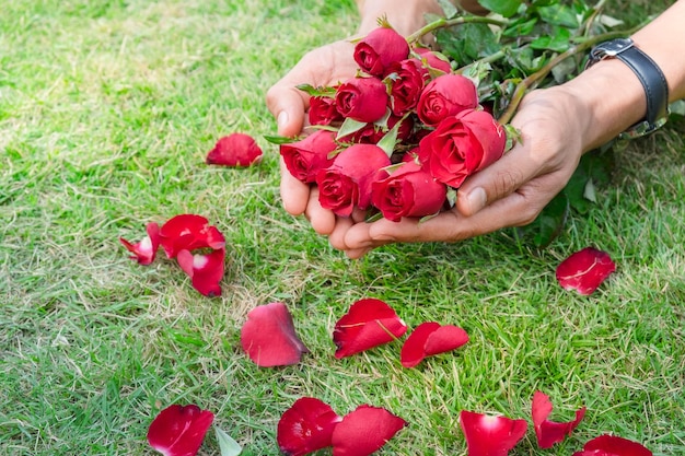 Photo close-up of hands holding roses on grass