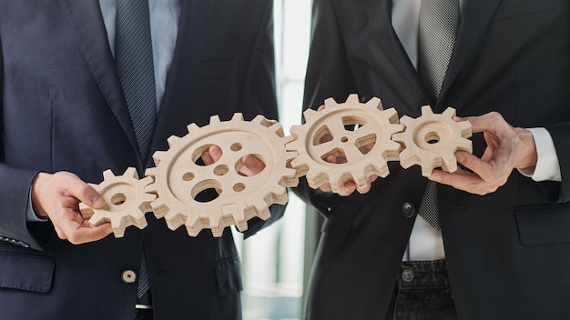 Photo close up hands holding round wooden figurines on the background of office worker