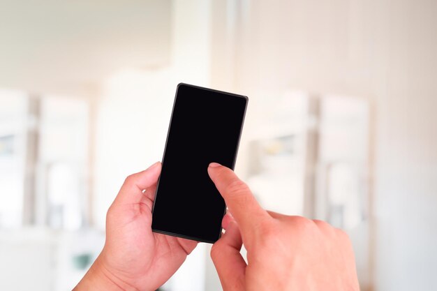 Close up of hands holding smartphone with blank screen over blurred background