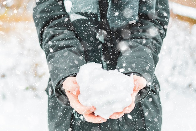 冬の日の屋外で雪を保持している手を閉じる