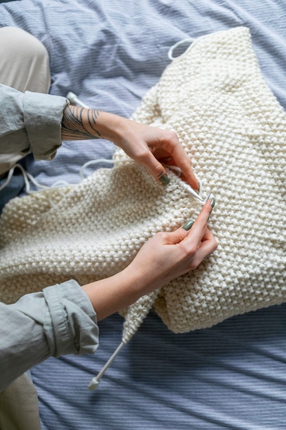 Foto chiuda sulle mani che lavorano a maglia all'interno