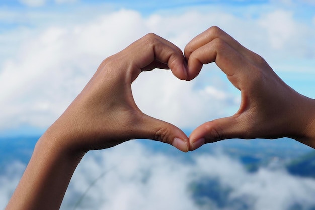 Photo close-up of hands making heart shape against sky