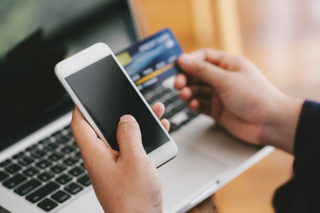 Close up hands making online payment. Man's hands holding a credit card and using smart phone for online shopping