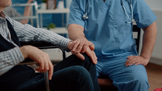 Close up of hands of man nurse comforting senior patient