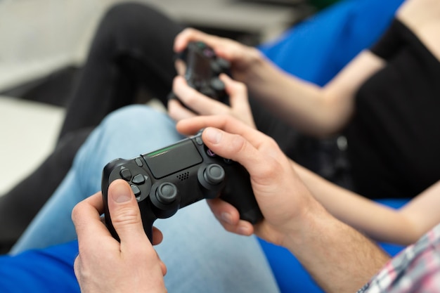 Close-up of the hands of a man and a woman enjoying playing\
video games with a console gamepad in their hands.