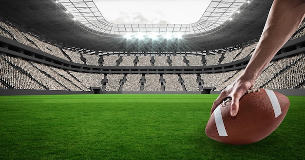 Close up of hands placing a rugby ball on grass field against stadium in background