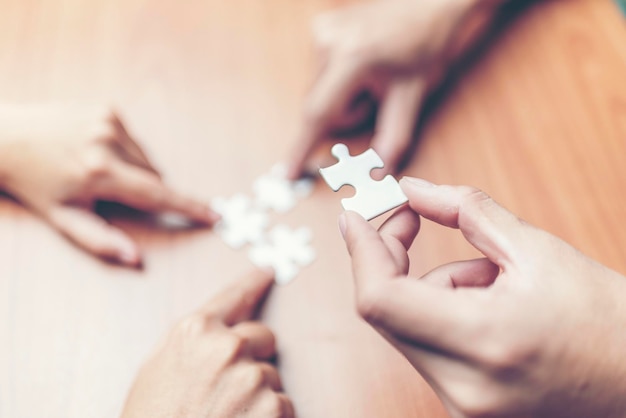 Photo close-up of hands playing jigsaw puzzle on table