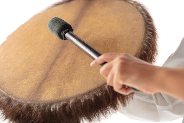 A close up of hands playing the tambourine percussion on white studio background