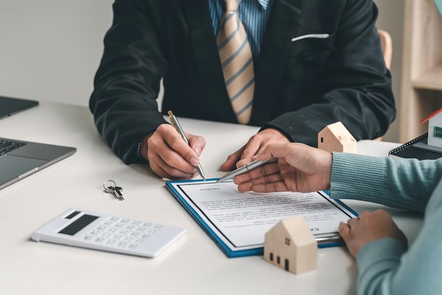 Close-up of hands of real estate agent and customer signing agreement to buy sell house at the office.