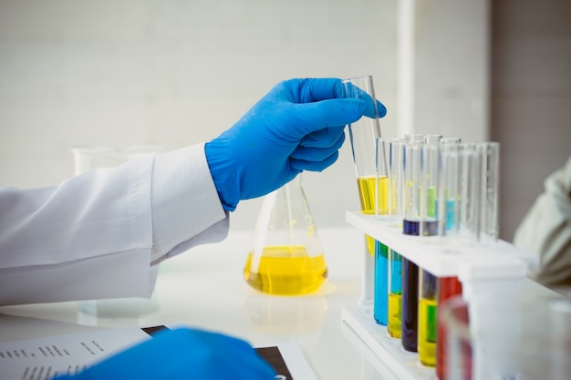 Close up hands of scientists are holding a test tube with a clear solution 