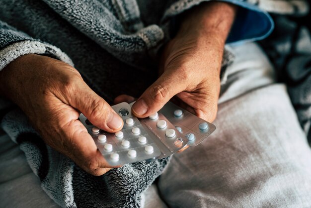 close up of hands of senior man taking or choosing a pillow to cure his fever and to be healthy and not sick 