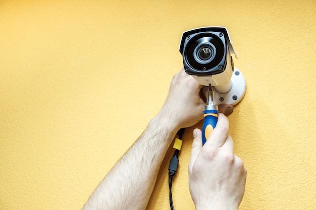 Close-up hands of technician adjusting CCTV camera