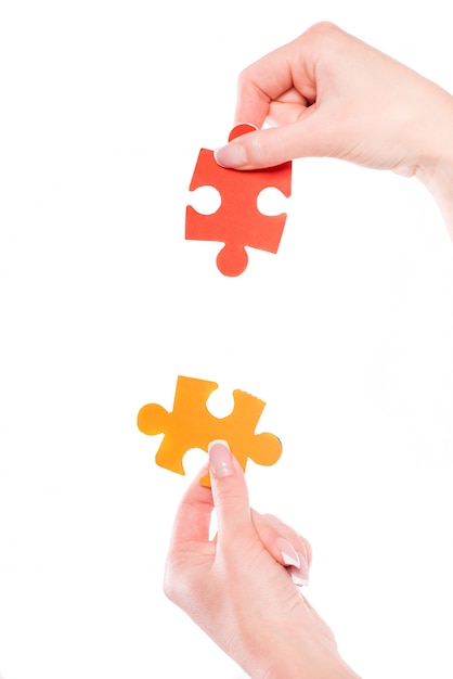 Close-up of hands trying to connect small jigsaw puzzles.