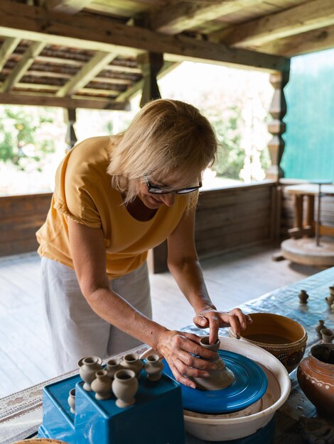 陶器をモデリングする陶器の車輪で互いに学ぶ2人の女性の手のクローズアップ