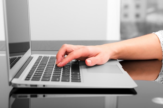 Close up of hands typing on a laptop in a coffee shop