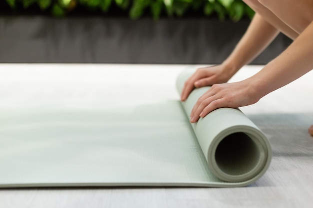 Close-up of hands unwinding a yoga mat.