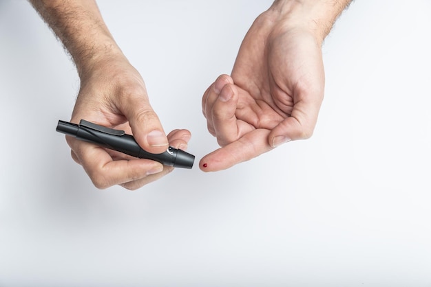 Close up of hands using lancet on finger to check blood sugar level by Glucose meter, Healthcare Medical and Check up, Medicine, diabetes, glycemia, health care and people concept.