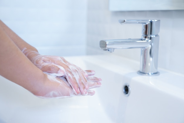 Foto chiuda in su delle mani che lavano con sapone nel lavandino