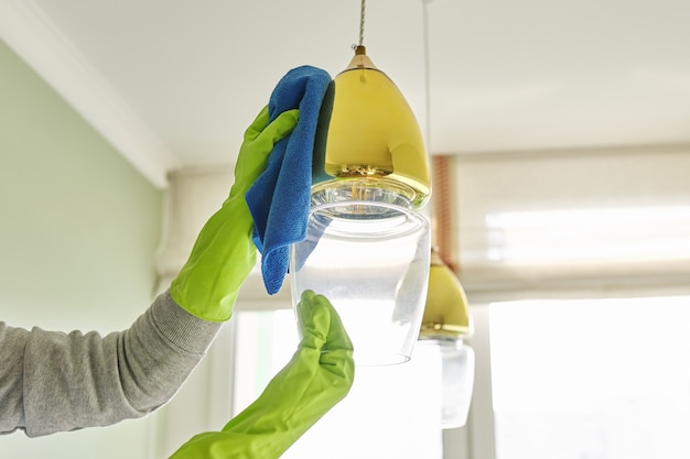 Close-up of hands with rag detergent, cleaning and polishing lamp