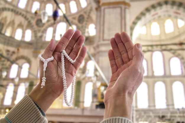 Close up hands with rosary beads praying inside the mosque\
faith religion islam concepts.