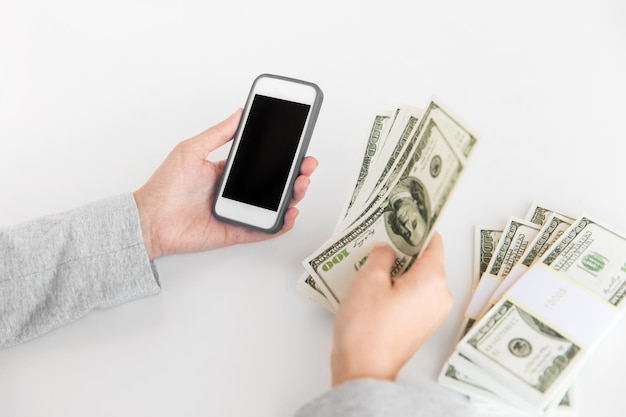 close up of hands with smartphone and dollar money