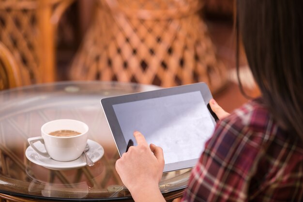 Primo piano della donna delle mani che utilizza il suo pc della compressa nel caffè.