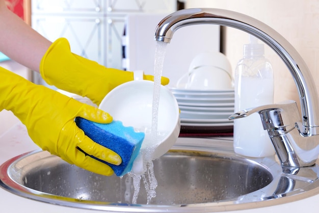 Close up hands of woman washing dishes in kitchen