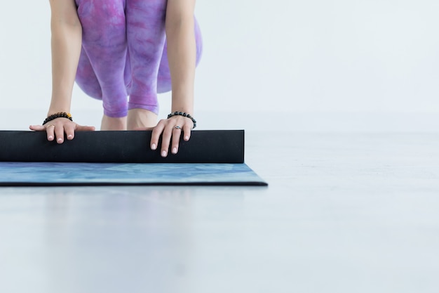 Крупный план на руках женщина йоги закатывает свой синий коврик после йоги