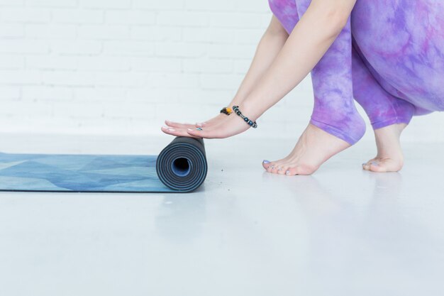 Close-up on hands yoga woman rolling her blue mat