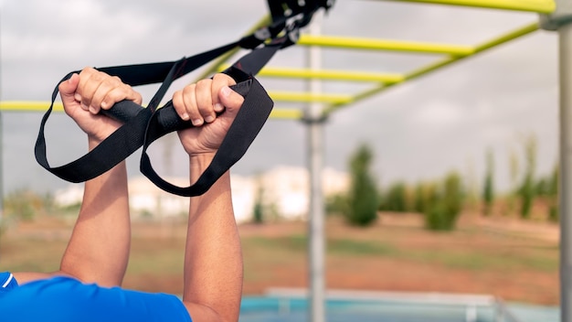 Close up hands of young man doing fitness exercises on a special hanging device