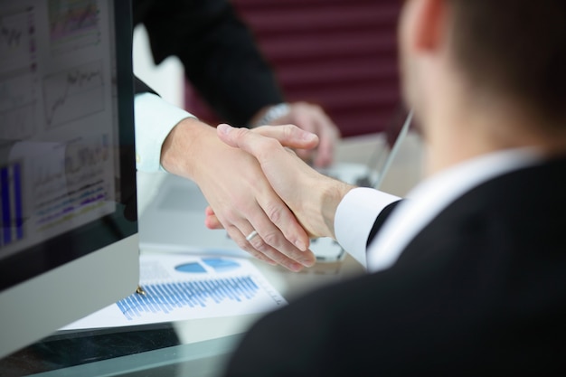 Close up handshake of business partners above the desk
