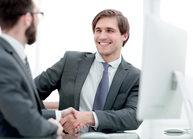 Close up handshake business partners sitting at the Desk