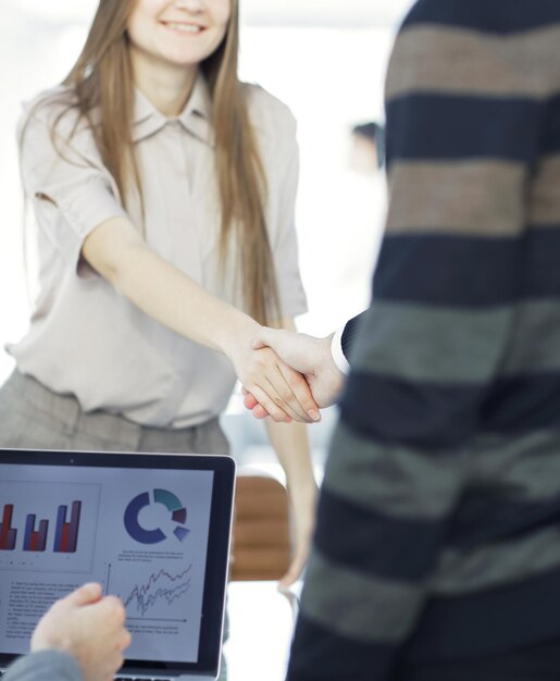 Foto chiudere la stretta di mano di dipendente e cliente in un ufficio moderno