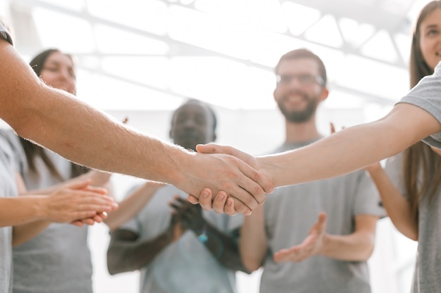 Avvicinamento. stretta di mano di due studenti sullo sfondo della squadra di studenti. foto con copia spazio