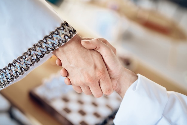 Close up handshake with chessboard