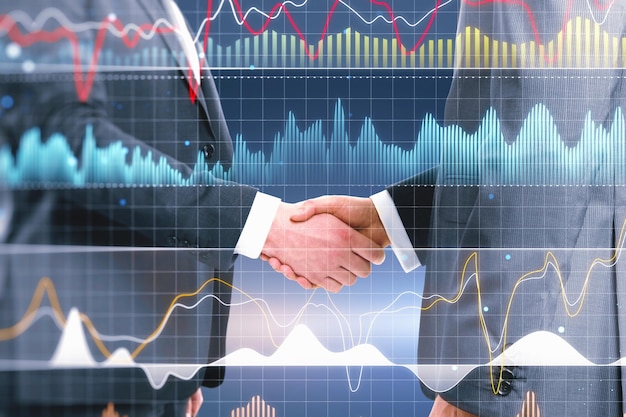 Close up of handshake with digital business graph hologram on blurry blue background Trade teamwork finance and analysis concept Double exposure