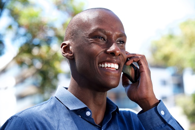 Close up handsome african man talking on mobile phone outside 