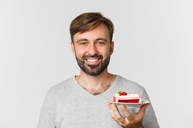 Close-up of handsome bearded man, smiling and holding cake