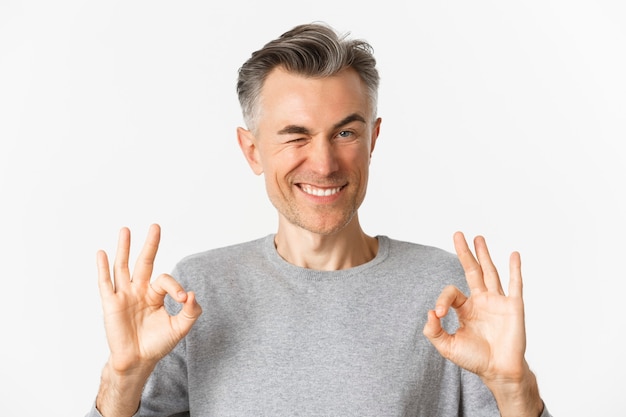 Close-up of handsome and confident middle-aged man, showing okay signs