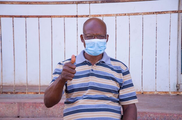 Photo close up of a handsome elderly african man wearing face mask preventing, prevented, prevent himself from the outbreak in the society.