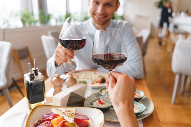 Close up of handsome gentleman and lady clinking glasses of alcoholic drink in cafe