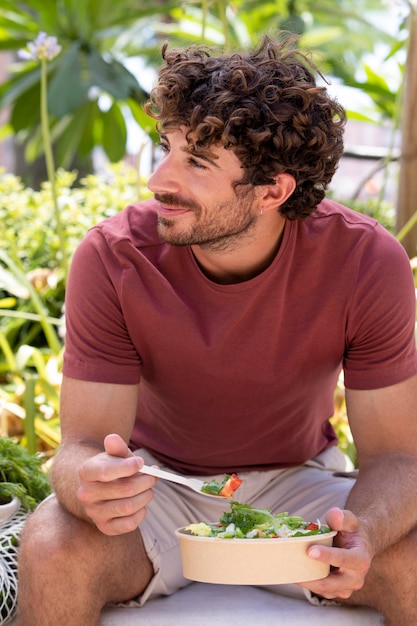 Photo close up on handsome man eating in park