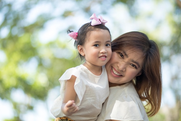 Close up happiness face of asian mother and little daughter toothy smiling outdoor