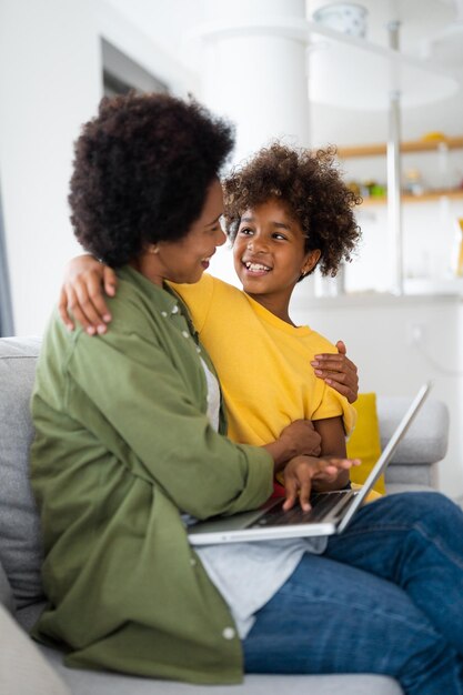 Close up of happy African American mother and daughter embracing each other while watching movie on laptop