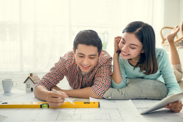 Close up of happy asian couple looking at blueprint at home